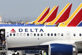 A Delta plane is seen in front of a row of Southwest Airlines planes, with their red and yellow tails visible.