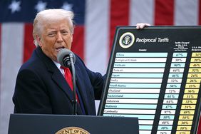 Donald Trump speaks at a podium while holding a chart of countries and tariff numbers.