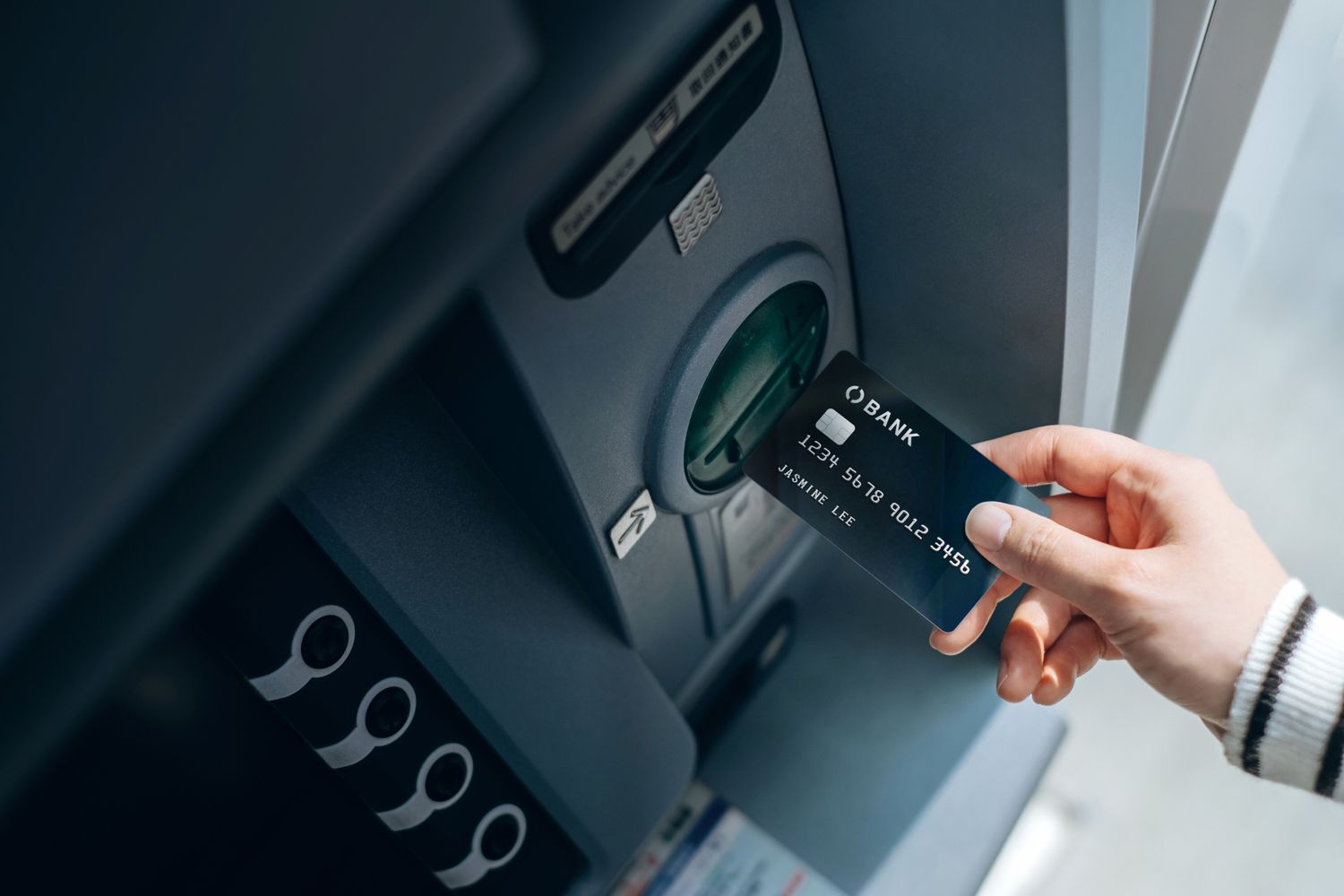 Person entering a credit card into an ATM