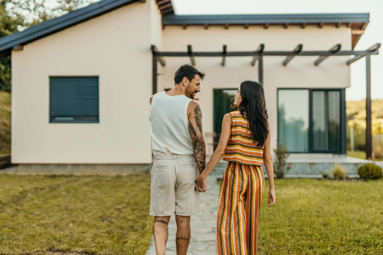 Happy young couple in front of the house they just bought with mortgage.