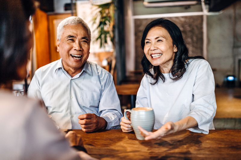 A couple in conversation have coffee at a table.