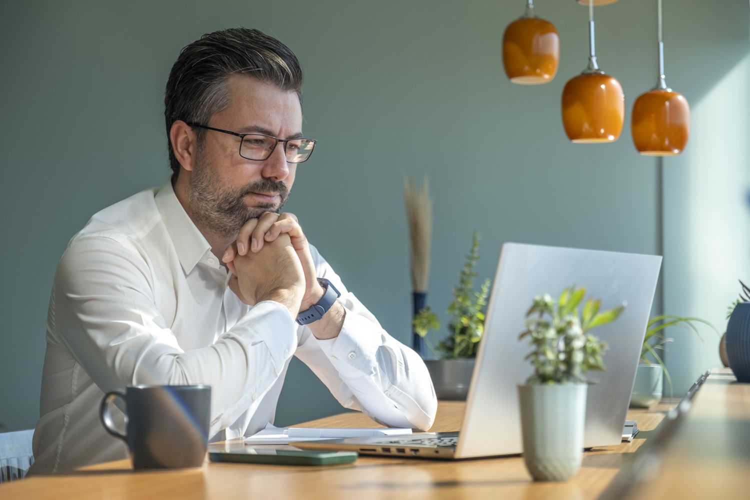 Man in his 50s sitting at a desk and looking intently at something on his laptop