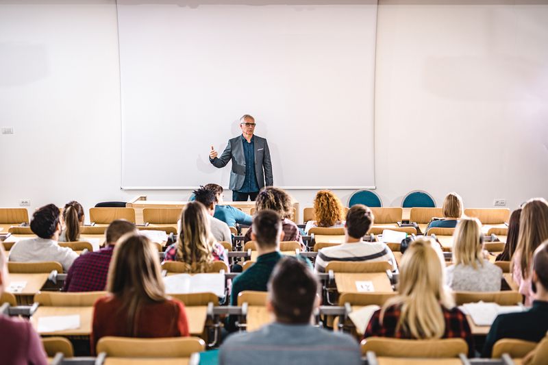 Senior Teacher Talking to Large Group of College Students in Amphitheater