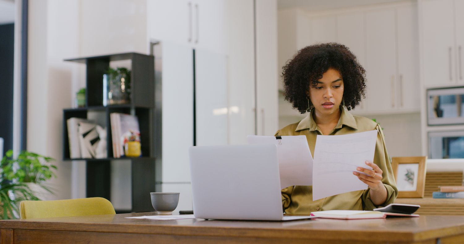 A woman reviews two documents.