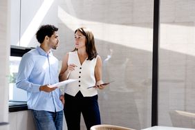 Investment professionals standing while having a discussion in an office.