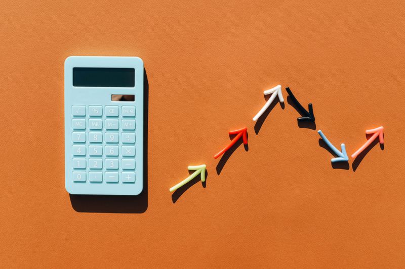 Blue calculator and a graph made from colored arrows. Brown background. Multi-colored lines in the graphics. Blue calculator.