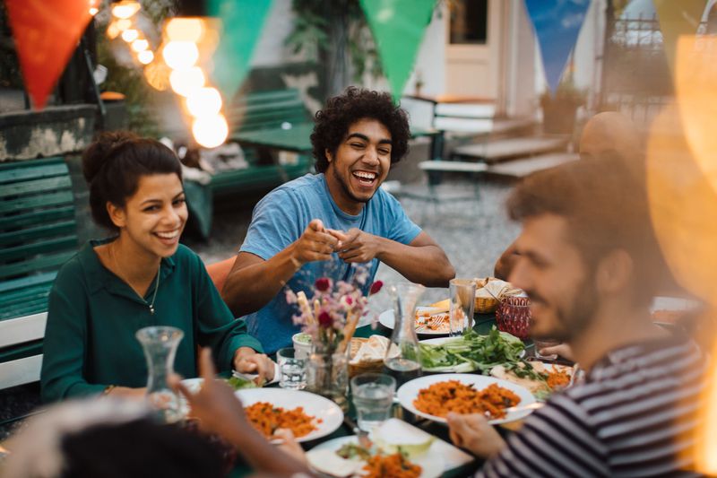 A group of friends sitting down outside and enjoying dinner.