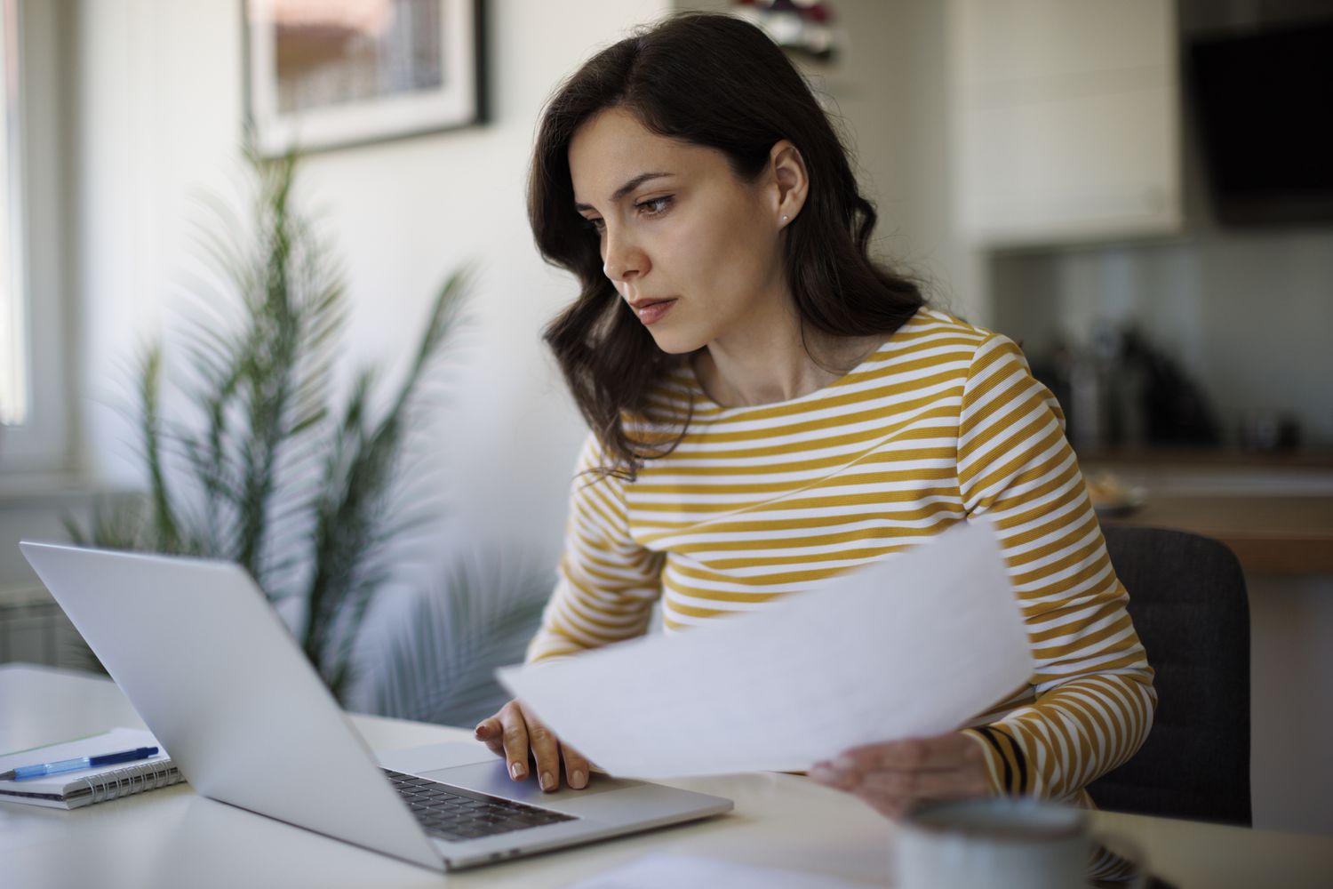 A woman reviews forms at a desk.