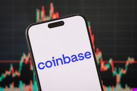 The blue Coinbase logo is seen on a smartphone screen, with a stock chart in the background.