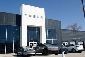 Tesla vehicles are seen in front of a black and white dealership building.