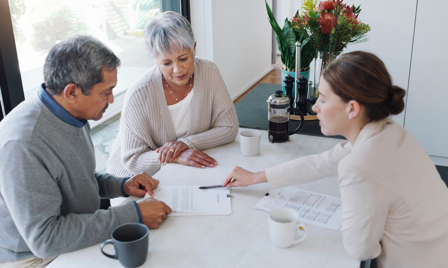 Woman sits across desk from older couple and shows them a document