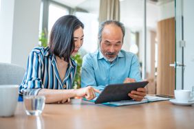 Older couple sitting at their dining room table and looking together at mortgage rates on a tablet