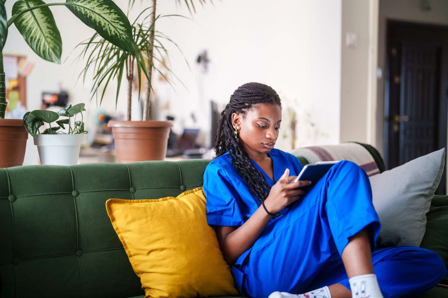 Woman in scrubs using digital tablet at home
