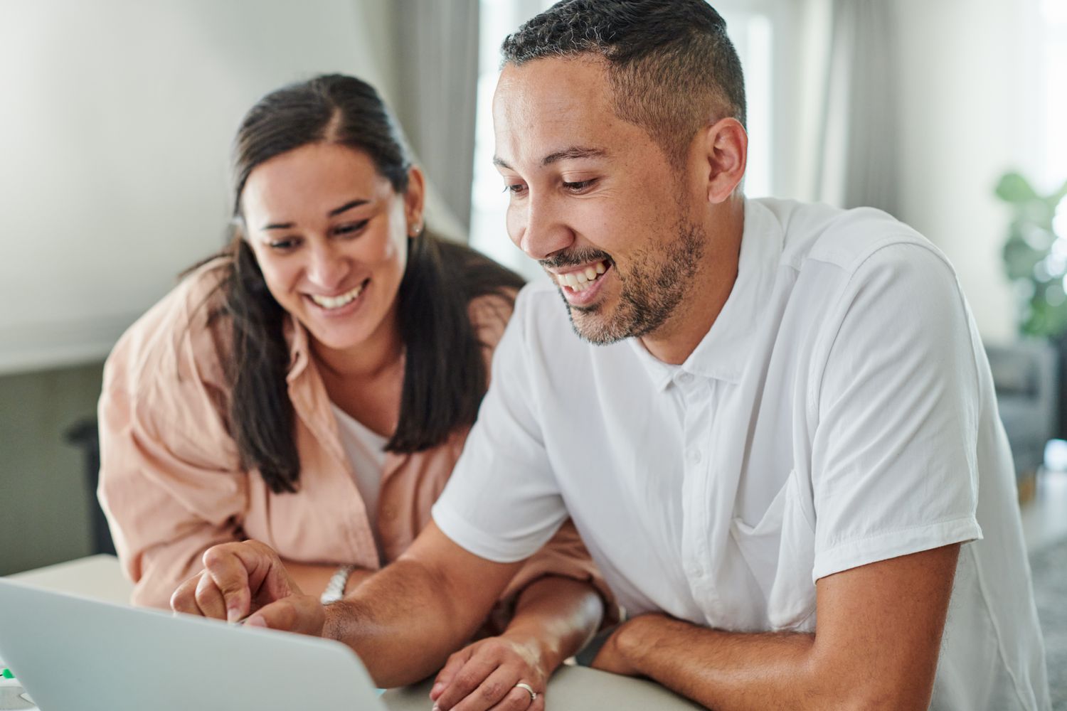 Young couple sitting at home and looking at online mortgage rates on a laptop