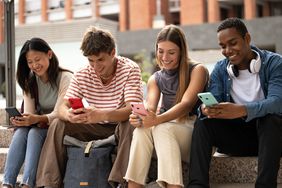 young people sitting in stairs while texting.Cheerful group of friends using their phones in the street. High quality photo