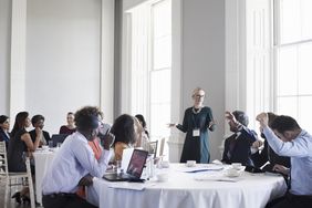 Shareholders raise their hands to vote for divesting a business unit with a split-off during an annual shareholder meeting.