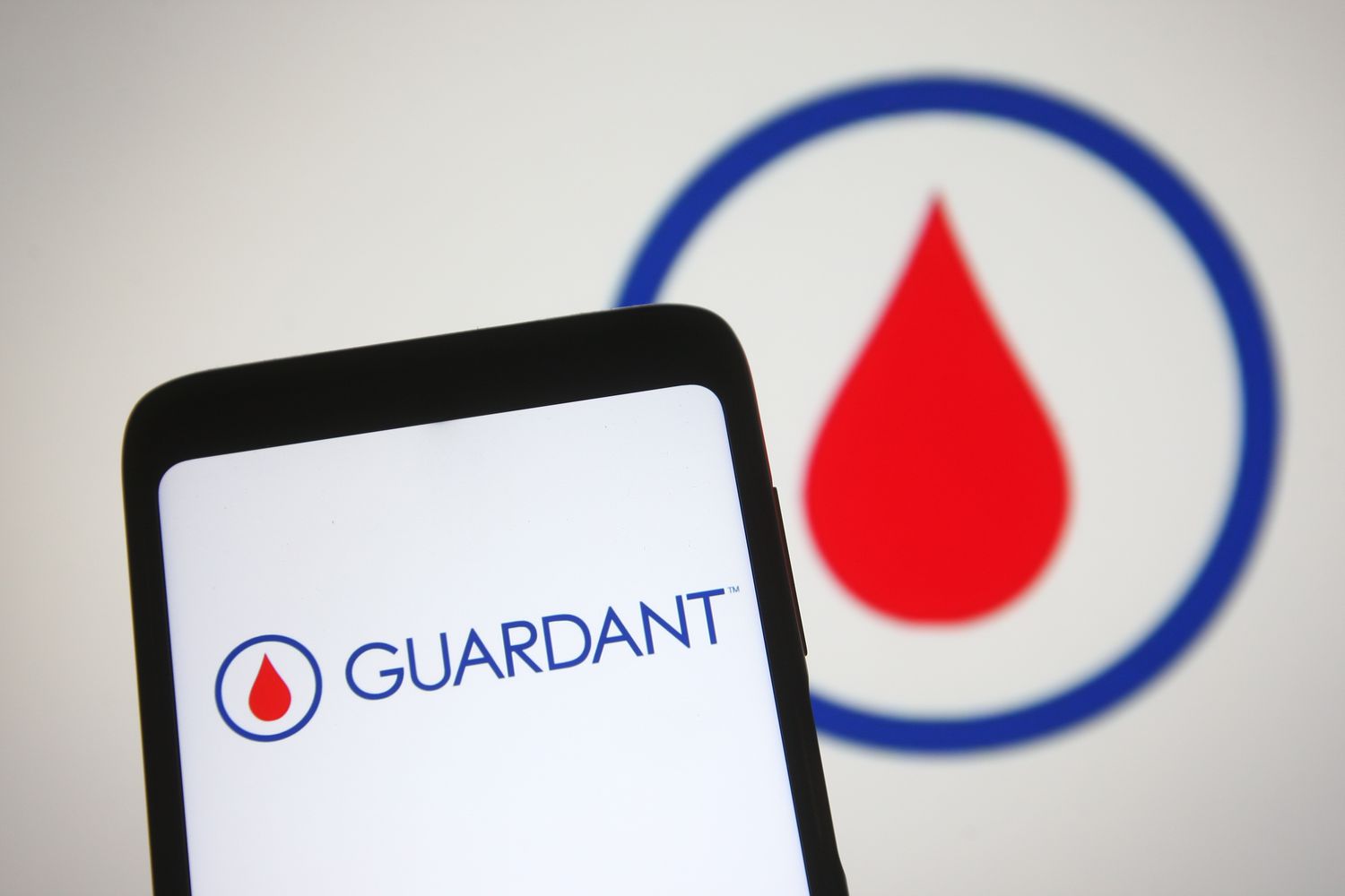 Guardant Health logo is seen on a smartphone and a PC screen