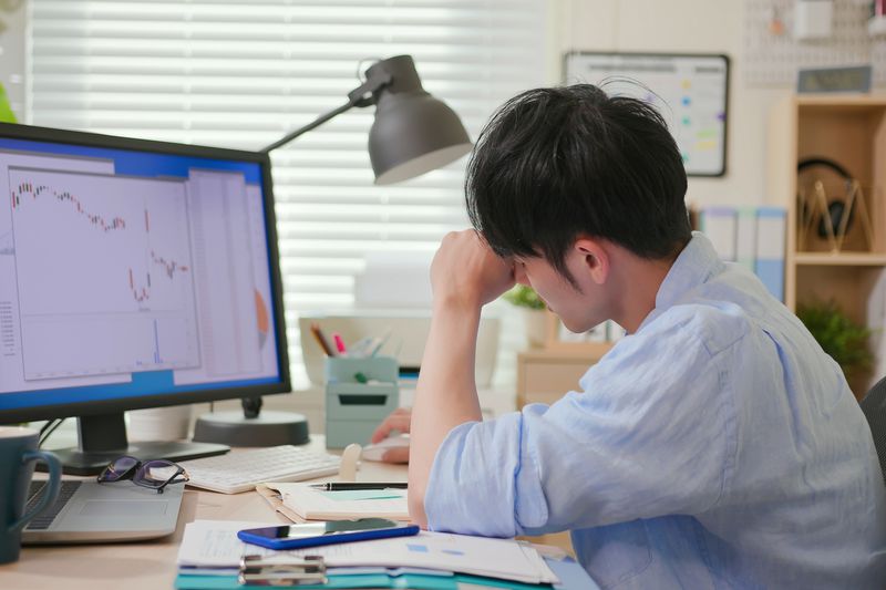 Worried investor looking at charts on a monitor.