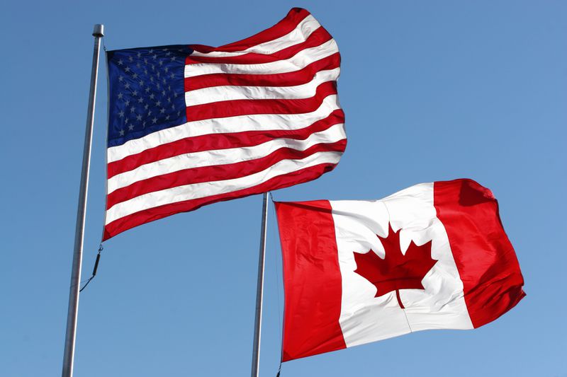 An American and Canadian flag waving in the wind