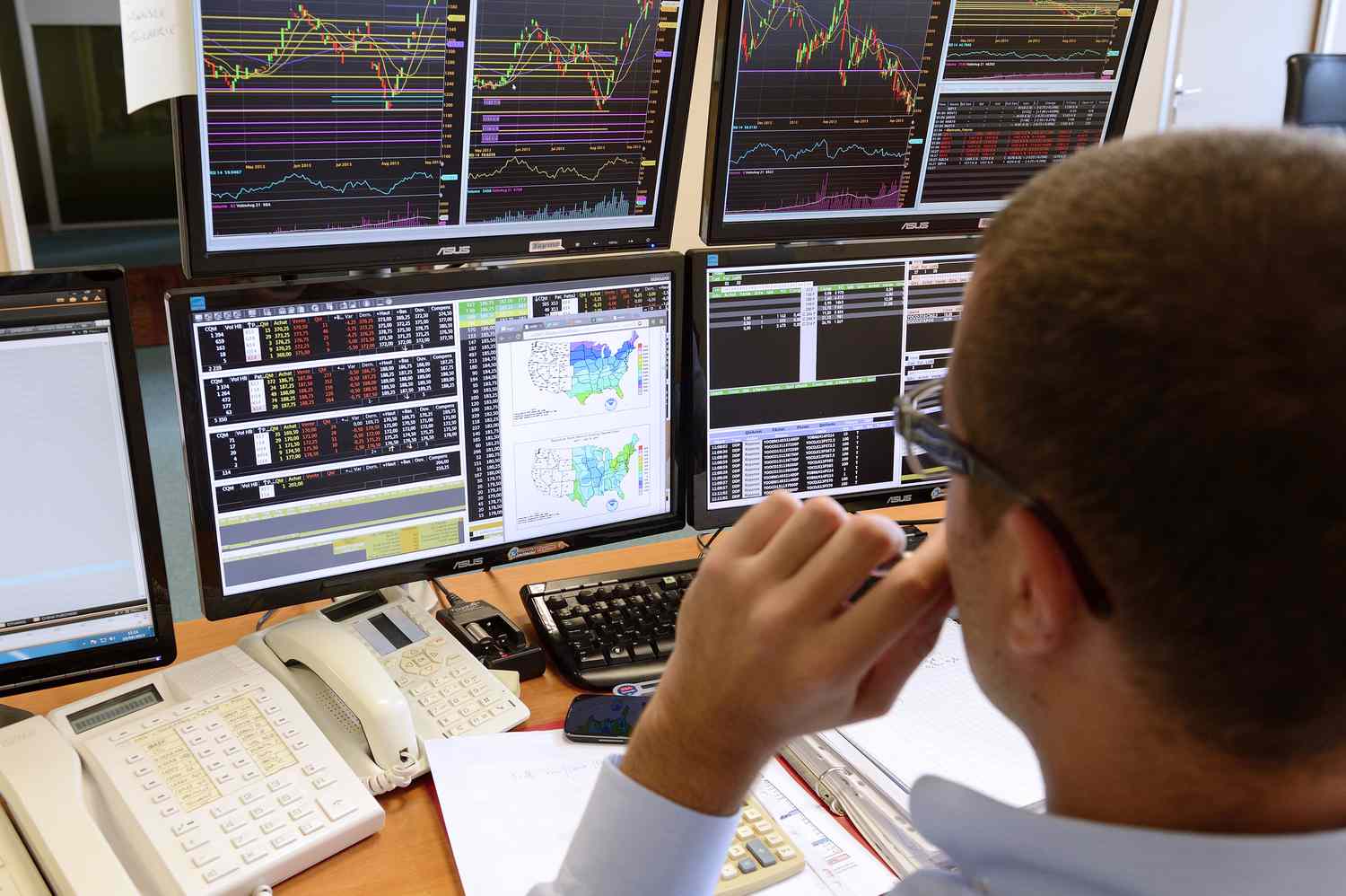 A trader looks at computer screens displaying charts for futures markets.