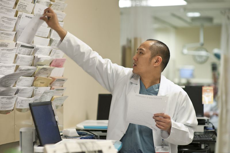 A doctor in a hospital selecting papers off the wall