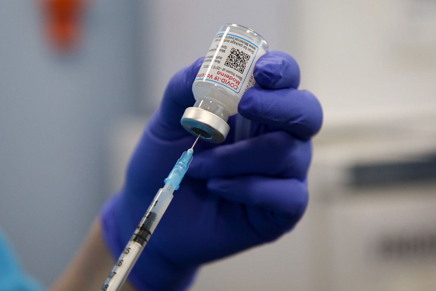 A health worker drawing the Moderna COVID-19 vaccine before administering a booster shot