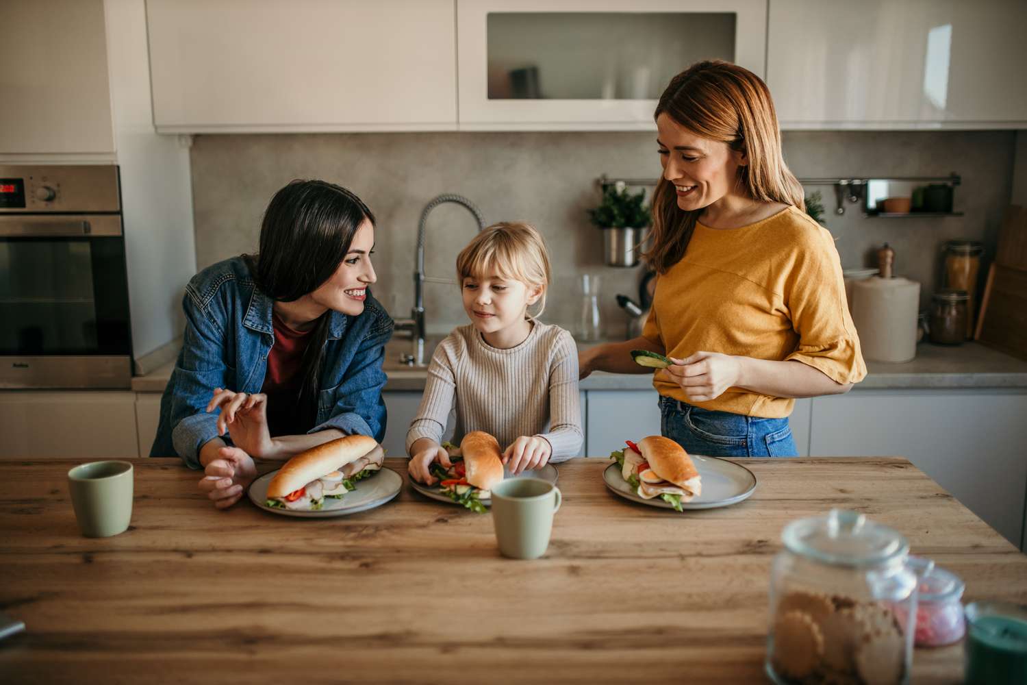 Happy family eating hot dog in their kitchen.