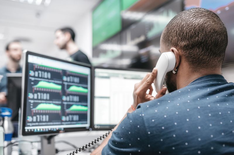 A worried investor on the phone with their broker trying to stop an order to sell holdings based on a price drop after an earnings report.