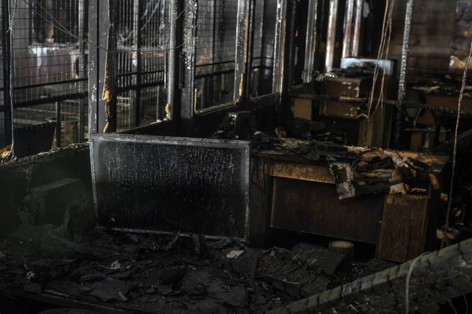Burned desks, computers, and office equipment litter the interior of an office gutted by fire.