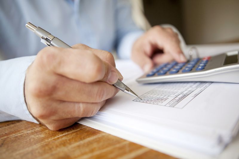 An accountant using a calculator and a pen.