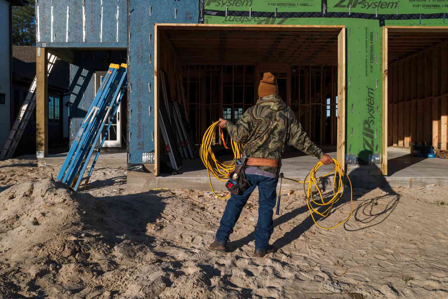 A worker coils an extension cord at a home under construction at the Waterways subdivision in Gulf Shores, Alabama, US, on Friday, Dec. 6, 2024.