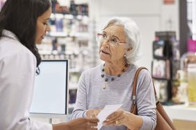 Older woman showing prescription to a pharmacist