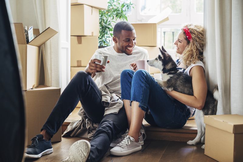 A happy couple sits among unpacked boxes in their new home. 