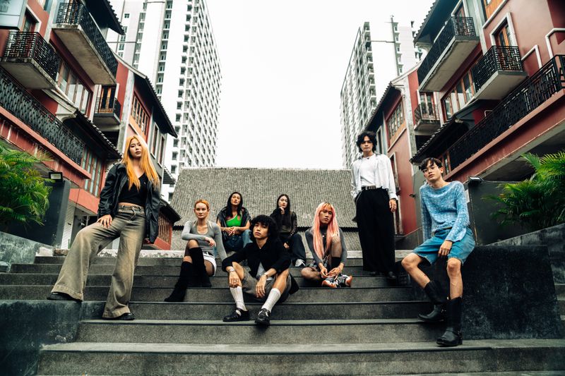 Group of young adults posing confidently on city steps in trendy streetwear.