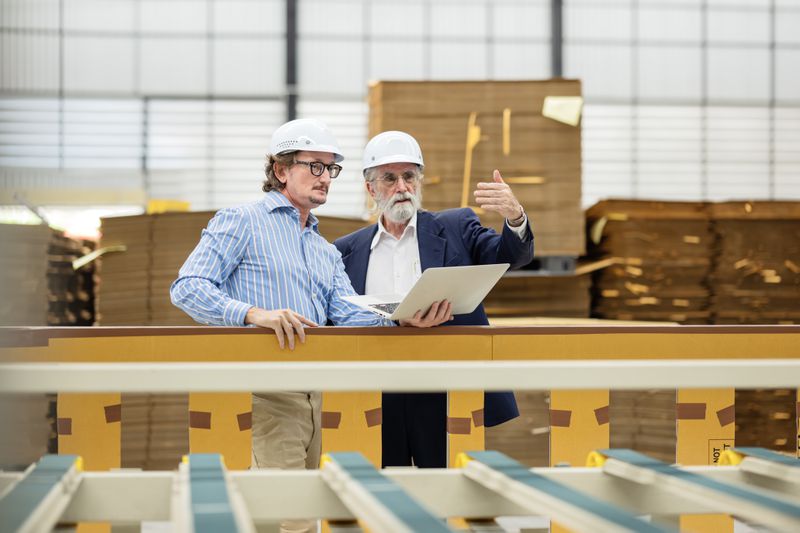 Business Partner having a discussion in front of the printing press machine of the corrugated box for an investment plan of the future.