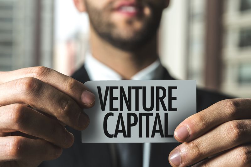 A man holding up a car saying venture capital