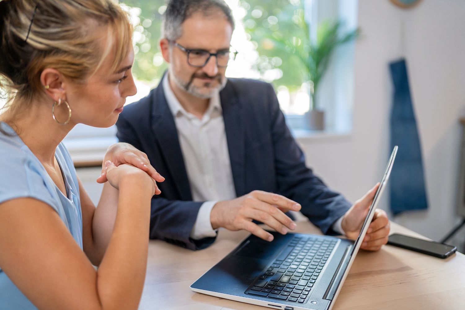 Older man explaining something on a laptop to a younger woman