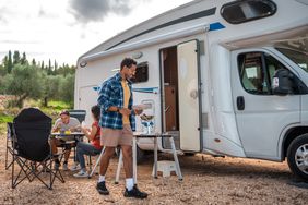 People hanging and having a picnic outside an RV on vacation.
