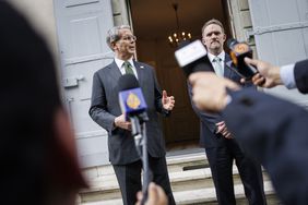 Scott Bessent and Jamieson Greer stand in front of the doorway at the residence of the permanent Swiss ambassador to the United Nations. Microphones are pointed toward them as they address reporters.