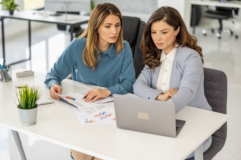 Two female businesswomen working together on a company project to issue CDs at the office