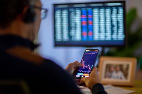 Trader looking at spread indicator chart inside trading app while considering trading positions.