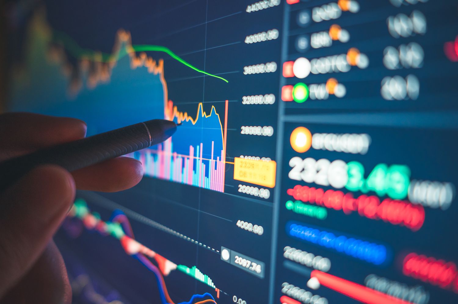 Person with a pen pointing to stock data on a screen