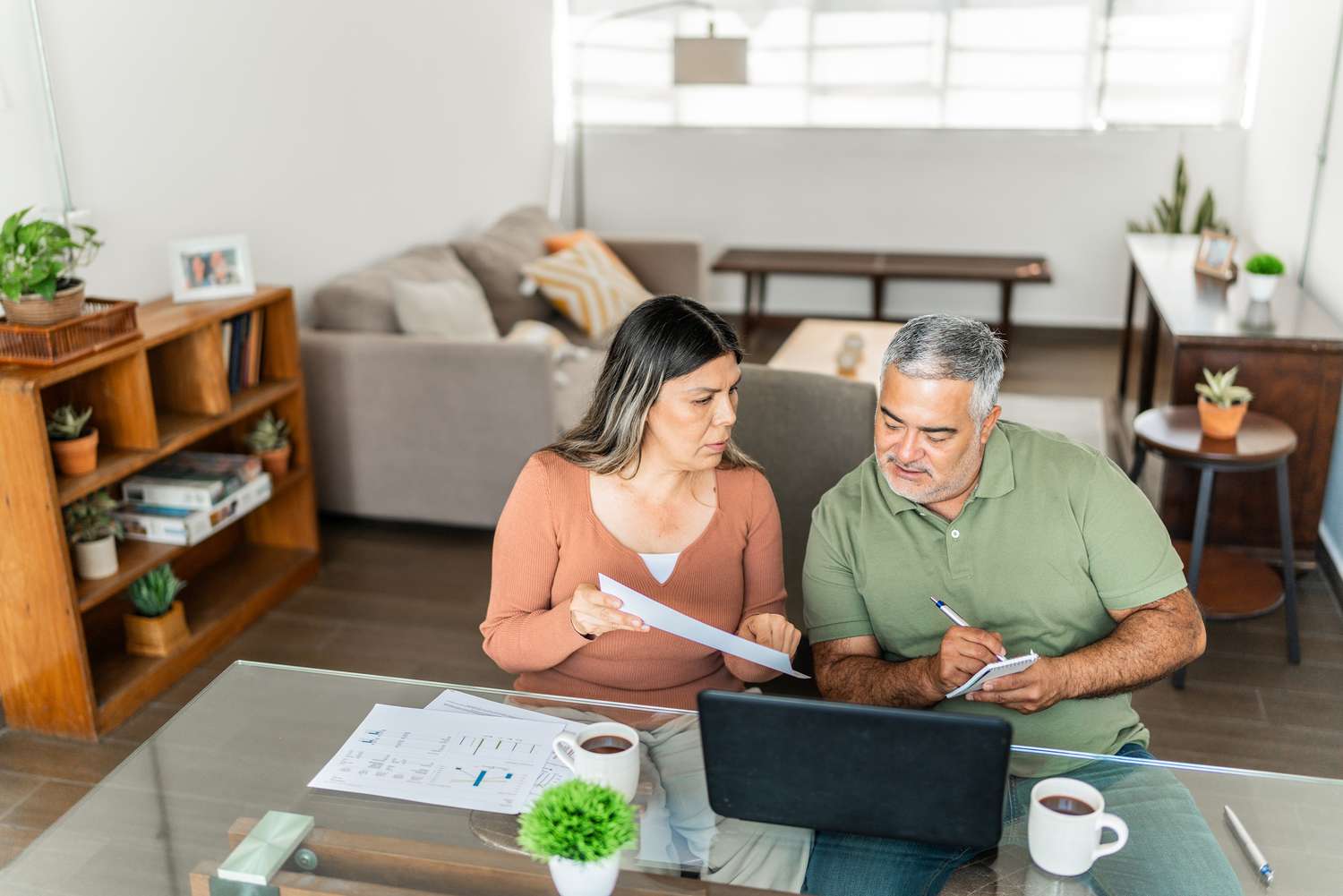 Mature couple talking and doing finances on home laptop.