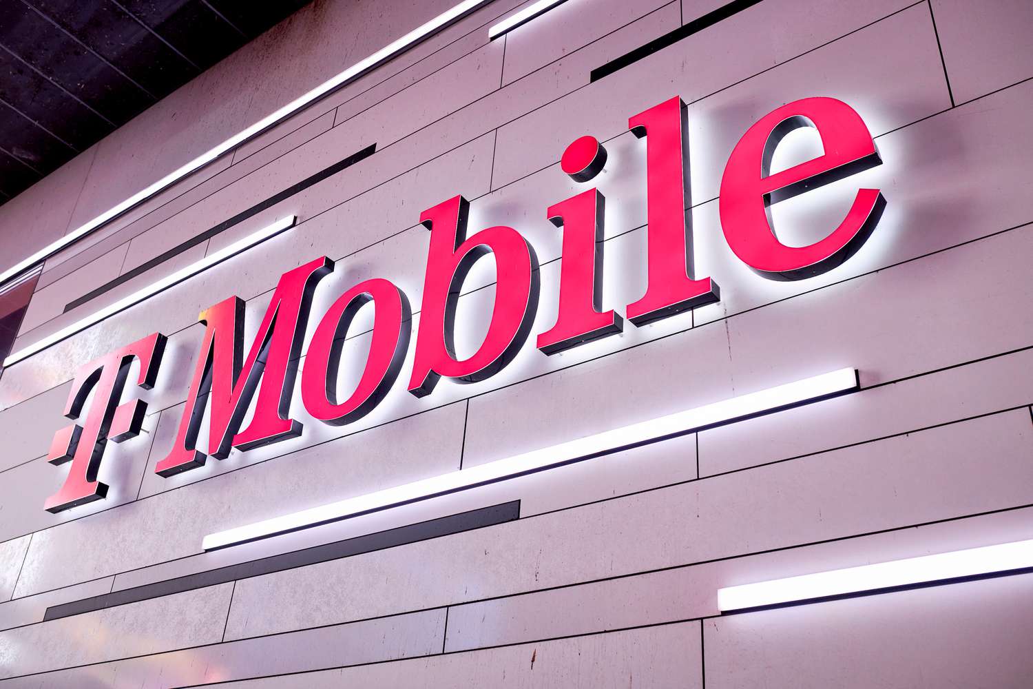 The pink T-Mobile logo is seen on the side of a white building.