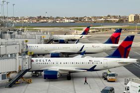 Three Delta Air Lines planes are seen next to an airport.