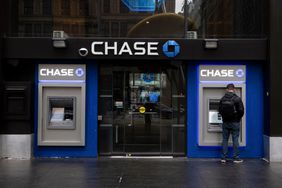 A man uses an ATM with the Chase logo visible above the two ATMs.