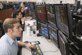 Profesional traders looking at screens with market data in a trading room