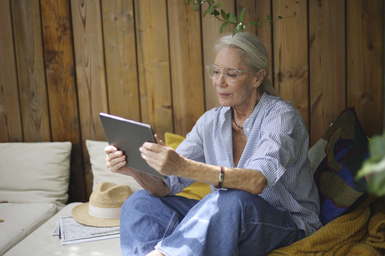 An older woman looking at a tablet on her balcony