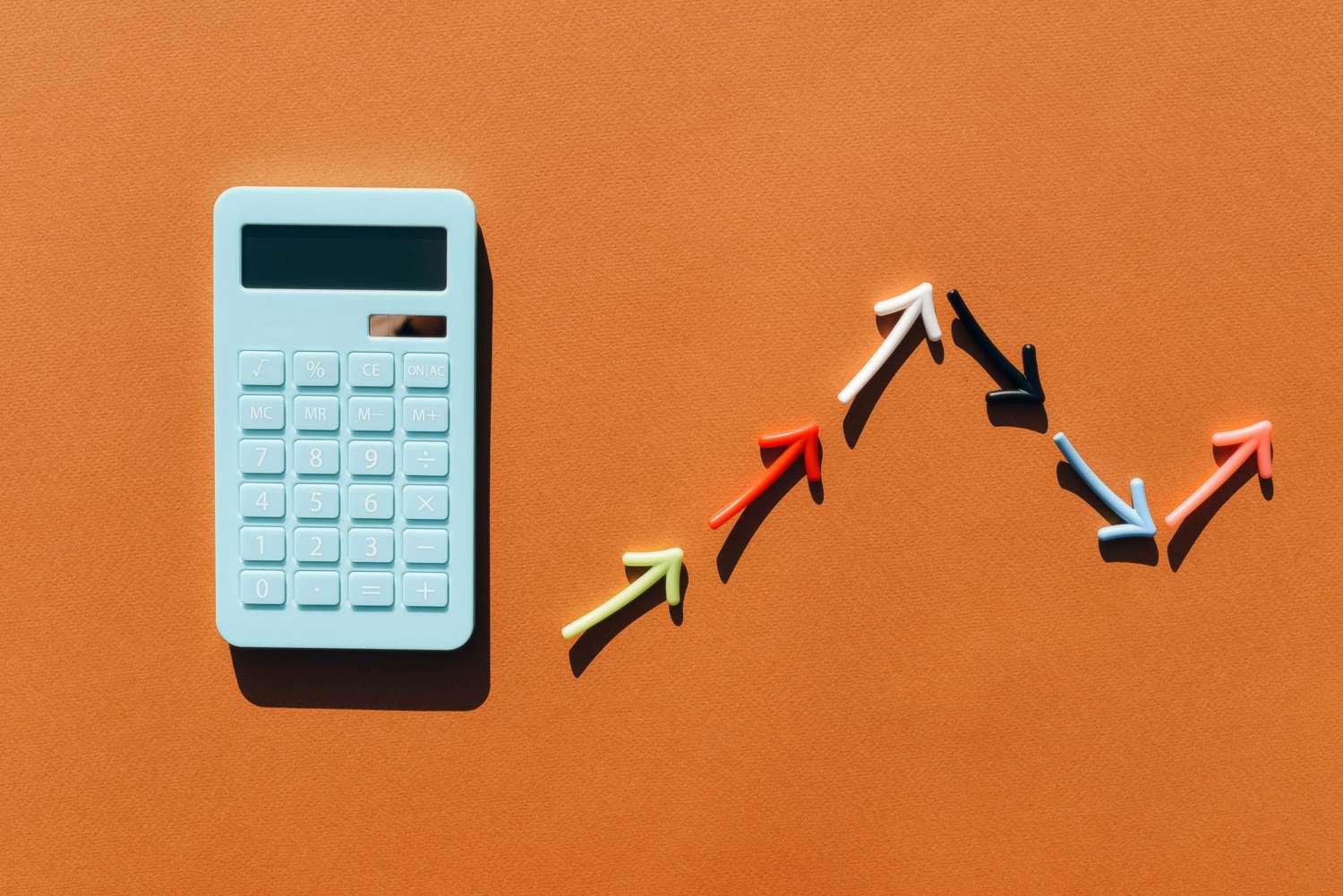 Blue calculator and a graph made from colored arrows. Brown background. Multi-colored lines in the graphics. Blue calculator.