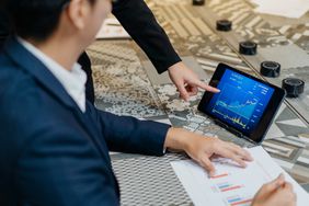 Two business men checking stock market chart on digital tablet